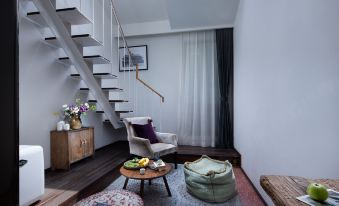 There is a living room adjacent to another area, featuring stairs, a table, and a chair in the center at Peking Yard  Boutique Hotel