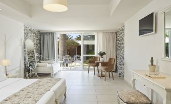 a large white bedroom with a bed , a chair , and a table in the room at Civitel Creta Beach