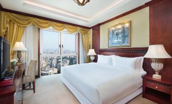 a large bed with white linens is in a hotel room with a view of the city at Hilton Beirut Metropolitan Palace
