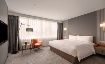 The bedroom is well-furnished with large windows, a bed, and a desk positioned in the middle at Pullman Shanghai Skyway Hotel