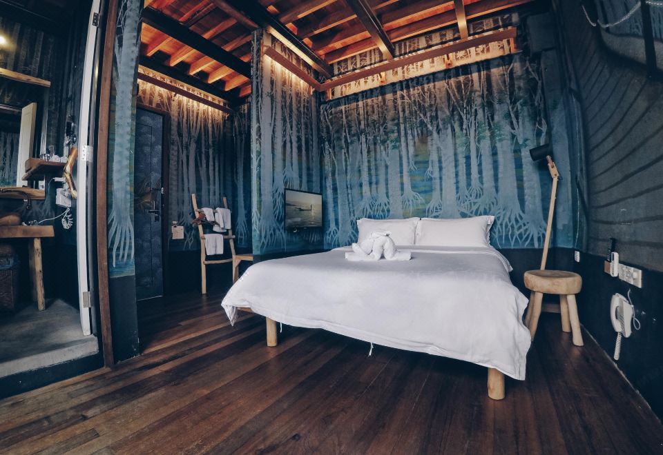 a cozy bedroom with a large bed , wooden floors , and a blue wall adorned with drawings at The Happy 8 Retreat @ Kuala Sepetang