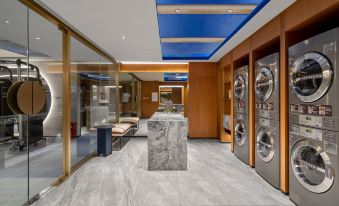 The second floor of the hotel features a spacious room with an open concept, laundry facilities in the middle, and an adjacent modern room with a kitchenette and a bathroom at Crystal Orange Shenzhen Nanshan Science and Technology Park