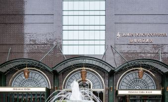 There is a sign indicating the front entrance of a large building with a water fountain in the foreground at Guangzhou Tianhe Taikoohui - Coffee Rupin Hotel