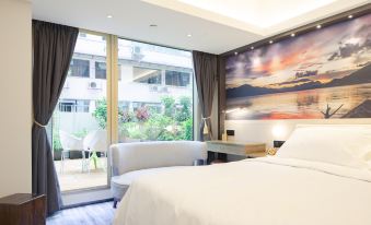 A modern bedroom with large windows and a balcony provides a view of the pool area at OASIS AVENUE – A GDH HOTEL