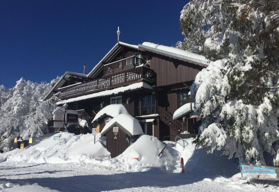 a large wooden house surrounded by snow - covered trees , creating a picturesque winter scene in the mountains at Karelia Alpine Lodge