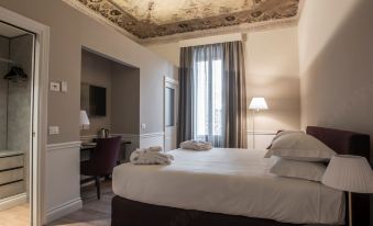 a large bed with white linens is in a room with a desk and chair at Palazzo Castri 1874 Spa & Garden