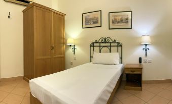 a neatly made bed with a white sheet and two pillows is in a room with wooden furniture at Hotel Kennedy Nova