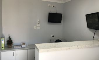 a small office space with a tv mounted on the wall , a desk , and a chair at Ulladulla Motel