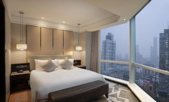 The bedroom features large windows and a balcony that overlook the city, with an unmade bed inside at Howard Johnson Huaihai Hotel Shanghai