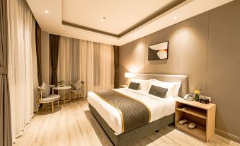 In the middle room of the hotel, there is a large bed accompanied by chairs and a table at Shanghai JOYFUL YARD Hotel (Shanghai Pudong Airport Store)