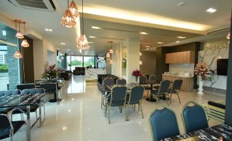 a large , well - lit room with multiple dining tables and chairs arranged for guests to enjoy a meal at Grand Inter Hotel