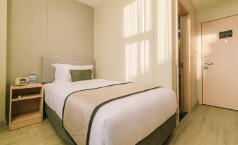 A bedroom with a large bed and a window in the middle, adorned with white sheets at Shanghai JOYFUL YARD Hotel (Shanghai Pudong Airport Store)
