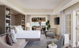 a luxurious hotel room with a large bed , multiple chairs , and a view of the ocean at The Ritz-Carlton, Laguna Niguel