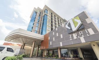 a modern hotel building with a large glass facade and a sign for zuz hotel at Zuri Hotel