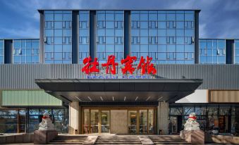 There is a front entrance to a hotel with an oriental-style sign above it, as well as another building nearby at Peony Hotel