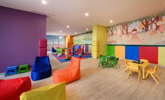 a brightly colored play area with multiple children playing in various colors and furniture such as bean bags at Oakwood Apartments Pik Jakarta