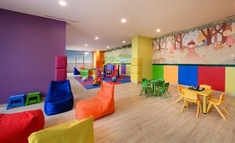 a brightly colored play area with multiple children playing in various colors and furniture such as bean bags at Oakwood Apartments PIK Jakarta