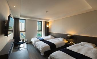 a hotel room with three beds , one on the left , one in the middle , and one on the right at Hotel the One