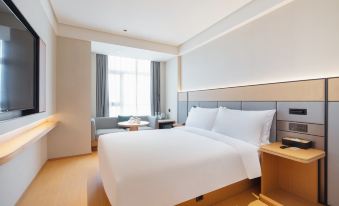 The bedroom features modern decor including large windows, a white bed, and a wood paneled accent wall at All Seasons Hotel (Guangzhou Tianhe Sports Center Branch)