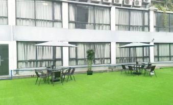 A patio with tables and chairs is covered by an artificial lawn at Yimi Hotel (Guangzhou Sanyuanli Subway Station Jinlong Tengfei Fashion City Branch)