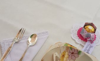 a dining table set with a white tablecloth , multiple forks , knives , spoons , and cups on the table at Reid's Place