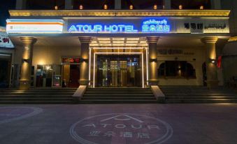 a hotel entrance with a neon sign above the door and steps leading up to it at Atour Hotel