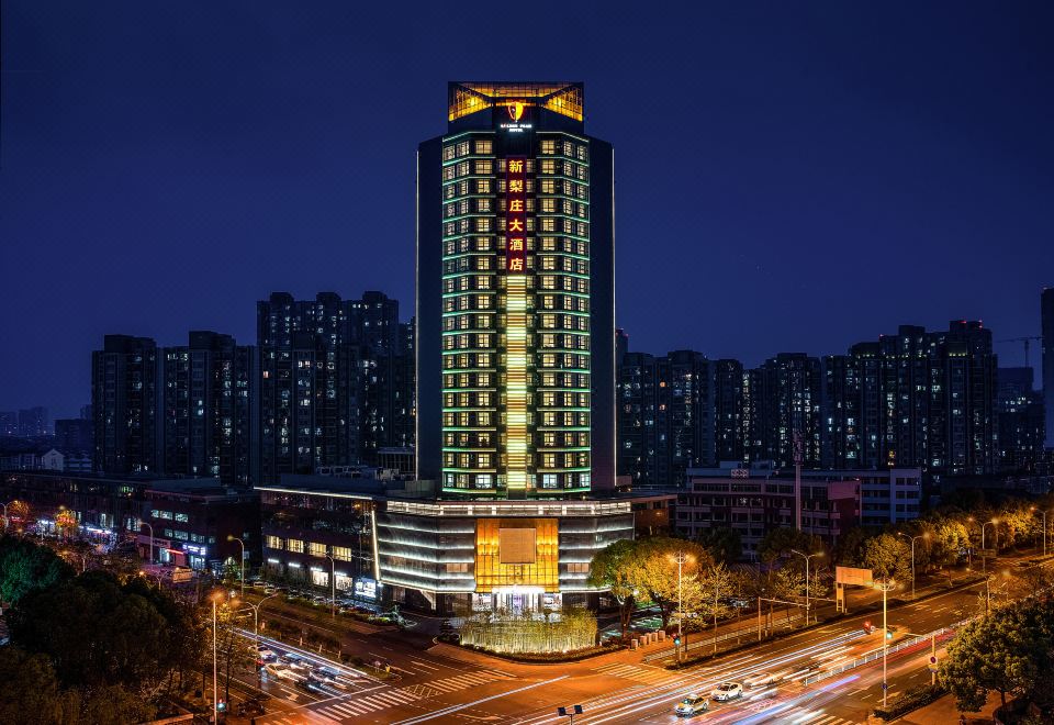 At night, a cityscape is illuminated by blue and white lights atop the buildings at Golden Pear Hotel