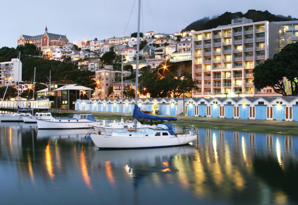 a marina with several boats docked in the water , surrounded by buildings and lit up at night at Copthorne Hotel Wellington, Oriental Bay