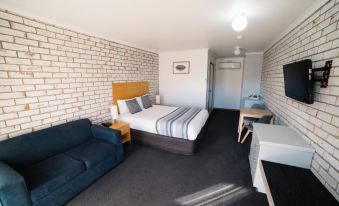 a hotel room with a bed , couch , and desk , along with a brick wall at The Heritage Bendigo