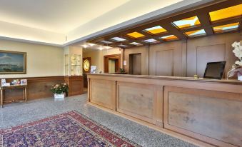 a wooden reception desk in a hotel lobby , with a potted plant and a carpet on the floor at Best Western Titian Inn Hotel Venice Airport