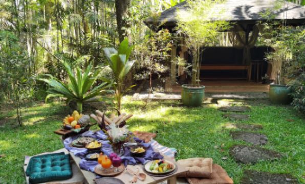a table is set up in a garden with various items , including a book and fruit at The Farm at San Benito, Autograph Collection