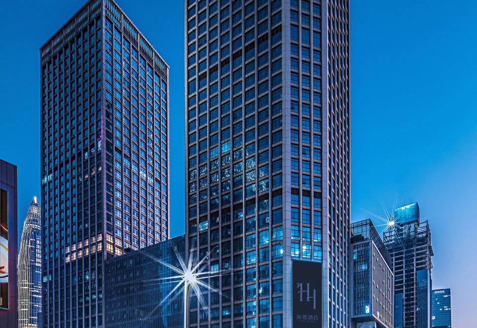 A cityscape of towering buildings with illuminated windows during dusk or nighttime at Shenzhen Hyde Hotel