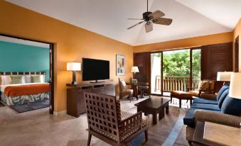 a living room with a television , chairs , and a sliding glass door leading to an outdoor patio at Fairmont Mayakoba