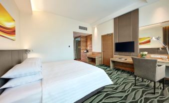 a modern hotel room with a large bed , tv , and desk , all set against white walls at Sunway Lagoon Hotel , Formerly Sunway Clio Hotel