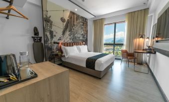 a modern hotel room with a large bed , wooden floors , and a view of the mountains outside the window at Travelodge Ipoh