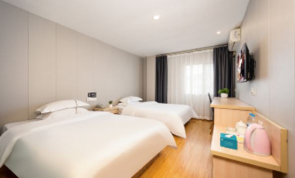 A bedroom with two white beds and a large window in the middle on one side at Seven Orange Hotel (Guangzhou Railway Station)