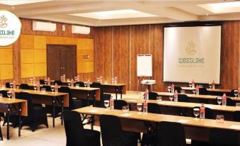 a conference room with wooden walls , a projector screen , and rows of chairs arranged for a presentation at The Westlake Hotel & Resort Yogyakarta