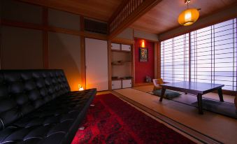 a cozy living room with a futon on the floor , a rug on the floor , and a doorway leading to a bedroom at Yufuin Bath Satoyamasafu