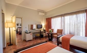 a hotel room with two beds , a tv , and a desk , all decorated in warm colors at Haile Resort Hawassa