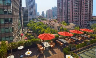 The high rooftop offers an outdoor patio with tables and chairs, providing a scenic view of the city at Kempinski The One Suites Hotel Shanghai Downtown