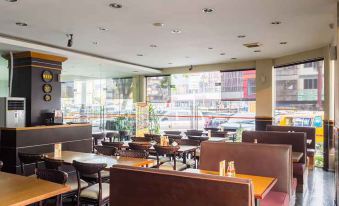 a modern restaurant with wooden tables and chairs , large windows , and a view of the city at Alpha Inn