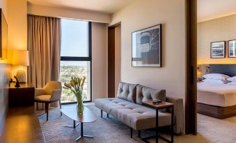 a living room with a couch , coffee table , and large window overlooking the city , along with a yellow chair and vase on the table at Hyatt Regency Andares Guadalajara