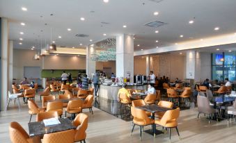 a large dining area with multiple tables and chairs , as well as a kitchen in the background at Swiss-Belhotel Kuantan