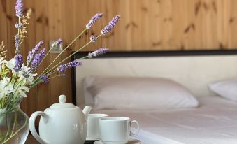 a bed with a wooden headboard and a white teapot on a table next to it , accompanied by a cup and a book at ELION
