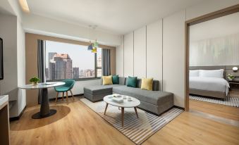 The apartment features a living room with a sofa, table, and a city view from the window at Holiday Inn Shanghai Nanjing Road