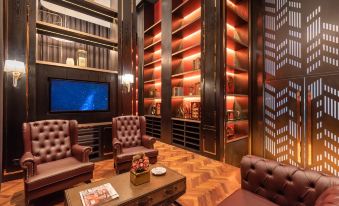 a well - decorated room with a large flat - screen tv mounted on the wall , surrounded by leather furniture and bookshelves at Ames Hotel