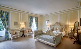 a luxurious bedroom with a large bed , two chairs , and a chandelier hanging from the ceiling at Eshott Hall