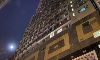 There is a tall building illuminated with lights in the city at night, with another hotel situated behind it at Ramada Hong Kong Grand