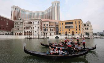 A group of gondolas is in front, with people walking down the street behind them at The Venetian Macao