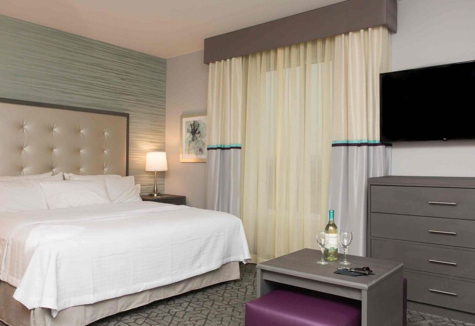 a hotel room with a king - sized bed , a tv , and a bathroom in the background at Homewood Suites by Hilton Allentown Bethlehem Center Valley